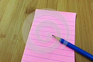 Blank pink notepad with pencil on table