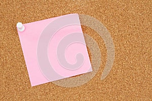 Blank pink sticky note on a bulletin board