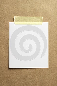 Blank polaroid photo frame with soft shadows and yellow scotch tape on craft cardboard paper background as template for graphic