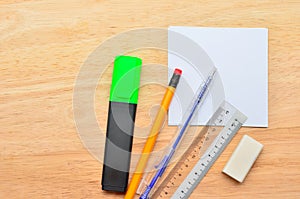 Blank post-it with pen, pencil, ruler, highlight market and eraser on office wooden table