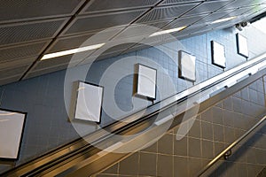 Blank poster or billboard in public place. Billboard mockup near to escalator in an mall, shopping center, airport terminal,