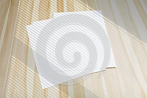 Blank poster flyer letterheads with window overlay shadow on light wooden desk as template for design presentation, event