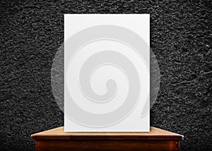 blank poster frame on wood table at black stone wall,perspective background