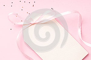 Blank price tag with pink ribbon bow on pink background.