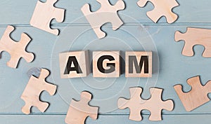 Blank puzzles and wooden cubes with the text AGM Annual General Meeting lie on a light blue background