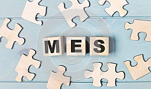 Blank puzzles and wooden cubes with the text MES Manufacturing Execution System lie on a light blue background