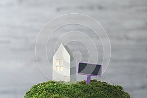 Blank real estate sign in front of house. Concept of sale, mortgage or rent. Miniature white house with a tablet