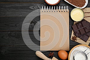 Blank recipe book and different ingredients on black wooden table, flat lay. Space for text