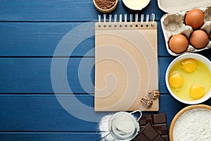 Blank recipe book and different ingredients on blue wooden table, flat lay. Space for text