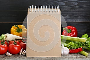 Blank recipe book and different ingredients on wooden table