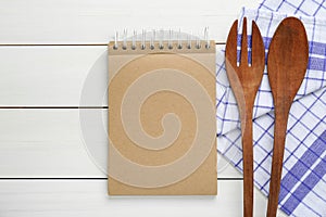 Blank recipe book and kitchen utensils on white wooden table, flat lay. Space for text