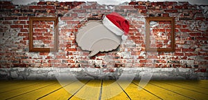 Blank recycled paper speech bubble with Santa hat on brick wall