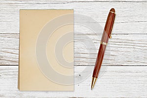 Blank retro old yellowed paper notepad with a pen