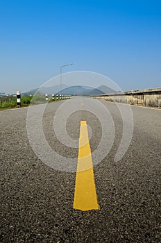 Blank road with mountain background, Focused at yellow line