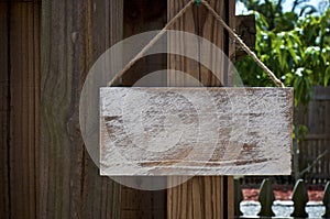 Blank rustic sign hanging from wooden fence