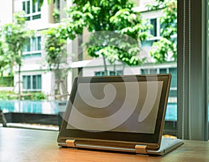 Blank screen of laptop for advertisement concept.Modern laptop with blank screen on the wooden table with background is green