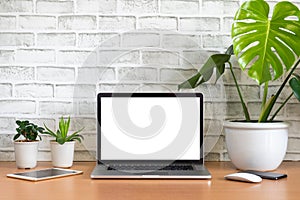 Blank screen of Laptop computer with tablet, mobile phone, mouse and monstera plant pots