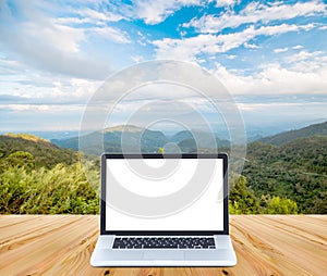 Blank screen laptop computer on wood with mountain and blue sky