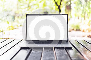 Blank screen laptop computer on wood table in outdoor cafe.