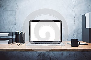 Blank screen of laptop on a wooden table and concrete wall