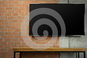 blank screen Led Tv on red brick wall with empty wooden table