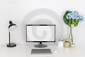 A blank screen PC and laptop with office supplies on white working desk.