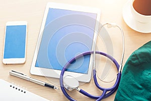 Blank screen tablet with medical objects on a desk as a metaphor