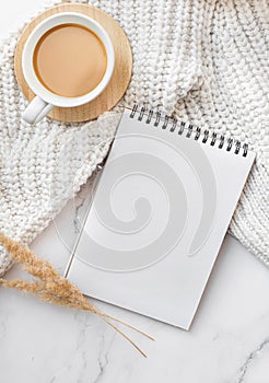 Blank sheet of paper notebook and cup on marble office desk.