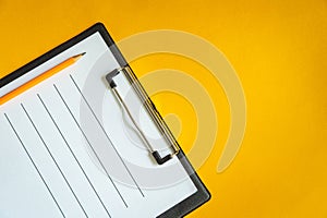 Blank sheet of paper and a pencil for writing on yellow office Desk