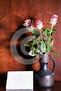 Blank sheet of paper and pink roses in ceramic jug