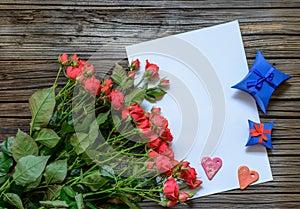 Blank sheet of paper on wooden surface with roses