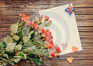 Blank sheet of paper on wooden surface with roses