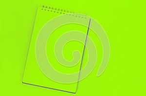 blank sheet of spiral notebook, cup of coffee on a green background