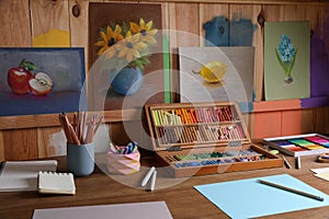 Blank sheets of paper, colorful chalk pastels and drawing pencils on wooden table indoors. Modern artist`s workplace