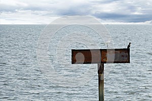 Blank Sign board iron on pole in the sea with reflection light in rippled effect textured water for design backgrounds and