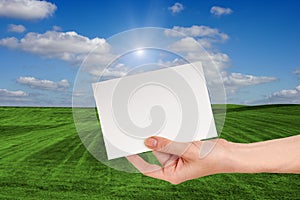 Blank Sign in Female hand Over Grass Field