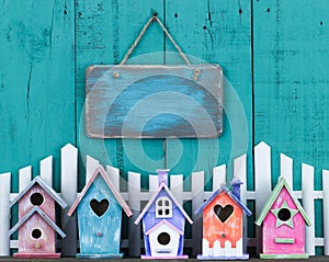 Blank sign hanging over fence and row of birdhouses