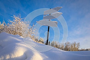 Blank signpost with three white arrows against beautiful blue sky in sunny frozen day. Blank track pointers or guide post on