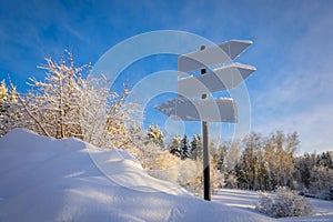 Blank signpost with three white arrows against beautiful blue sky in sunny frozen day. Blank track pointers or guide post on