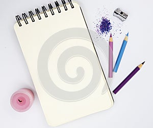 Blank sketchbook with pink violet pencils, and sharper white background. Artist table top view photo