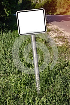 A blank small road sign next to the highway.