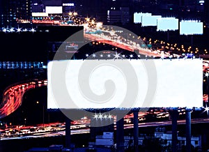 Blank space billboard at night with city traffic and car light as background, ready for advertisement