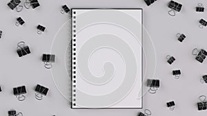 Blank spiral notebook with black binder clips on white table