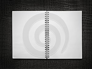 Blank spiral notebook on a black leather background