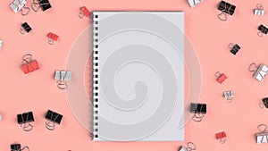 Blank spiral notebook with black, white and red binder clips on