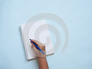 Blank spiral notebook with caucasian hand holding a blue pen ready to write.