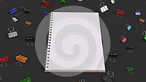 Blank spiral notebook with colorful binder clips on black table