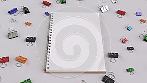 Blank spiral notebook with colorful binder clips on white table