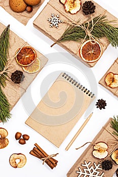 Blank spiral notebook and gifts boxes wrapped craft paper, decorated dried fruits, pine cones, fir branches. Zero wast Christmas c