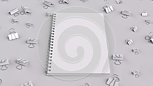 Blank spiral notebook with white binder clips on white table